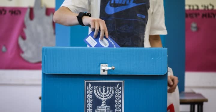 אדם מכניס מעטפה לתוך קלפי הבחירות