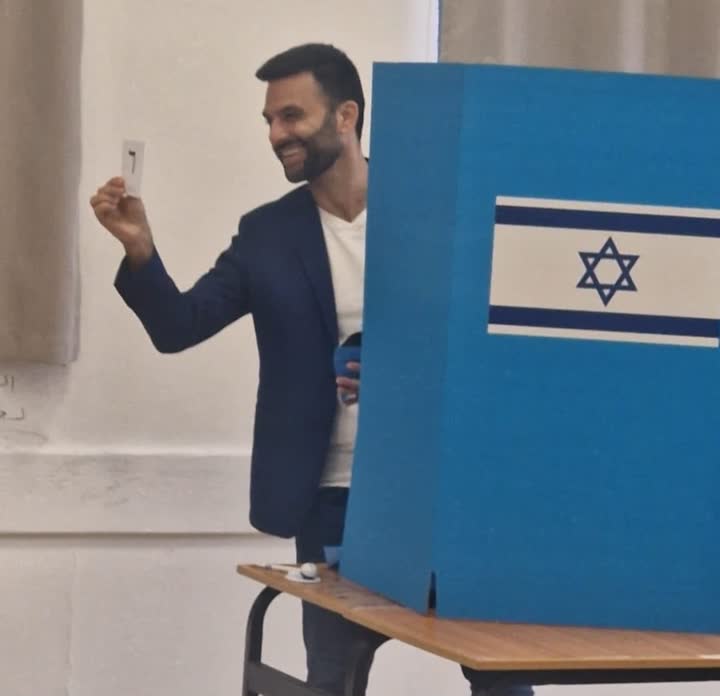 אדם מציג פתק הצבעה בקלפי