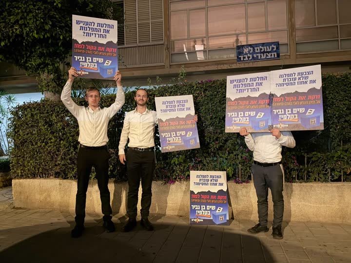פעילים מפגינים עם שלטים מול בית