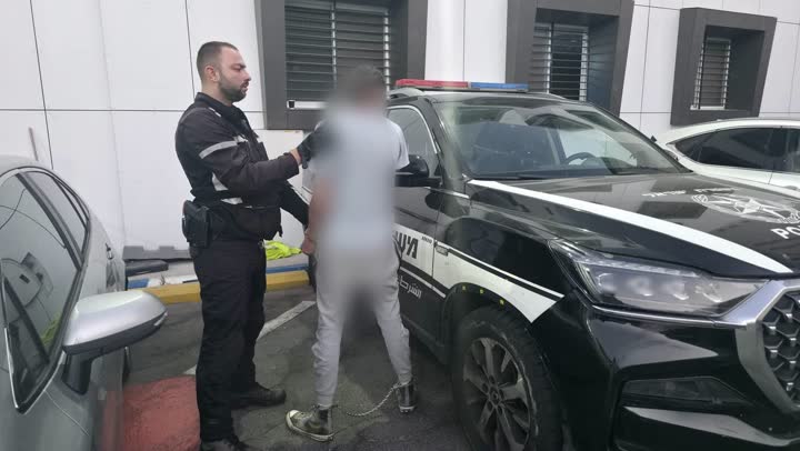 שוטר מעכב חשוד ליד ניידת משטרה