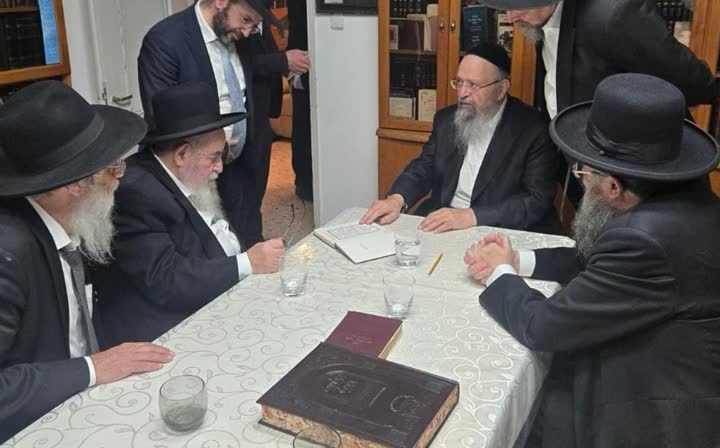 רבנים יושבים סביב שולחן בדיון